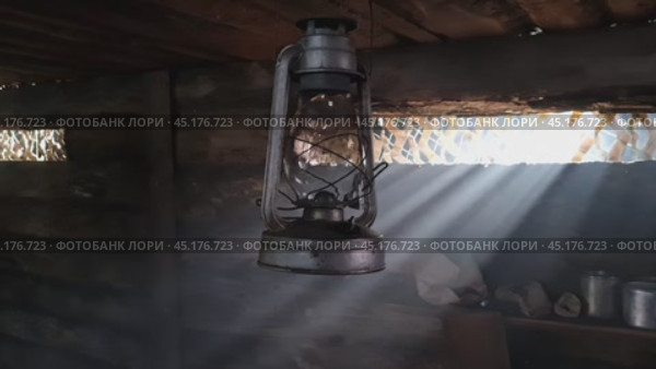A wooden dugout in which a kerosene lamp burns. Light from the window penetrates into the room. Стоковое видео, видеограф Александр Кузовков / Фотобанк Лори