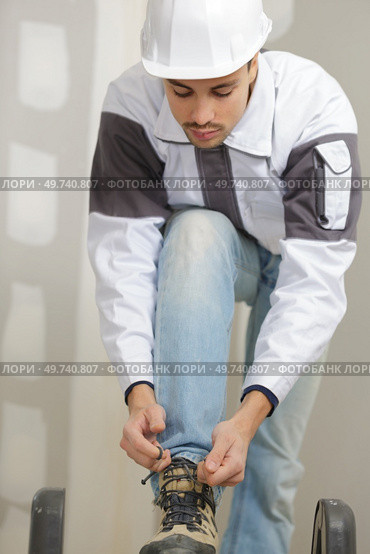 a worker tying shoe laces. Стоковое фото, агентство Ingram Publishing / Фотобанк Лори