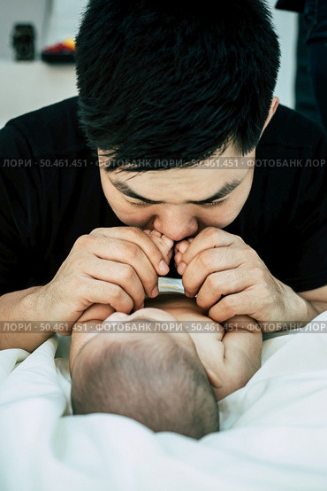 A young Asian father is sniffing his newborn baby. Стоковое фото, агентство Ingram Publishing / Фотобанк Лори