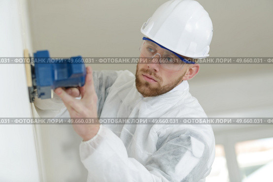 a young builder sanding wall. Стоковое фото, агентство Ingram Publishing / Фотобанк Лори