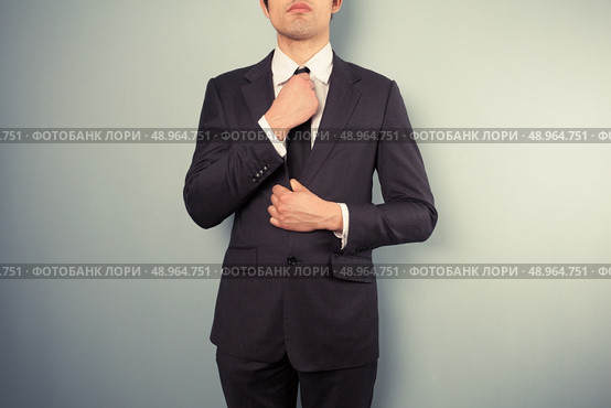 A young businessman is adjusting his tie. Стоковое фото, агентство Ingram Publishing / Фотобанк Лори