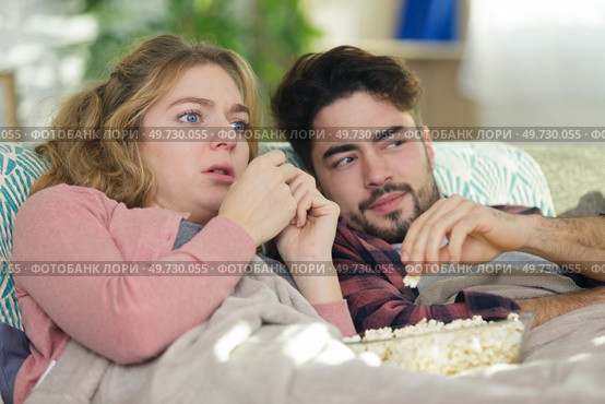 a young couple on the couch watching tv. Стоковое фото, агентство Ingram Publishing / Фотобанк Лори