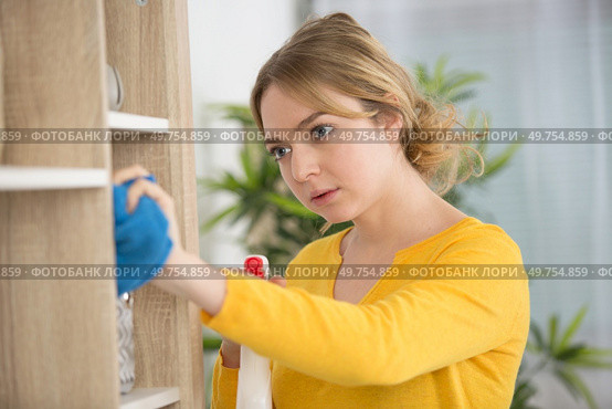 a young lady dusting bookshelves. Стоковое фото, агентство Ingram Publishing / Фотобанк Лори
