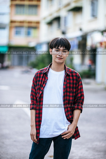 A young man in a striped shirt is standing on the street. Стоковое фото, агентство Ingram Publishing / Фотобанк Лори
