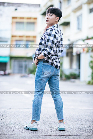 A young man in a striped shirt is standing on the street. Стоковое фото, агентство Ingram Publishing / Фотобанк Лори