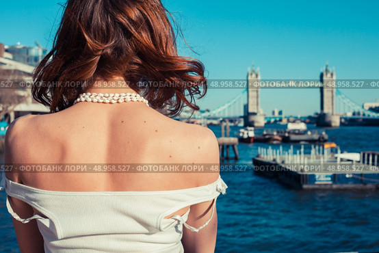 A young woman is tanning her back on a sunny day and looking at the river Thames in London, England. Стоковое фото, агентство Ingram Publishing / Фотобанк Лори