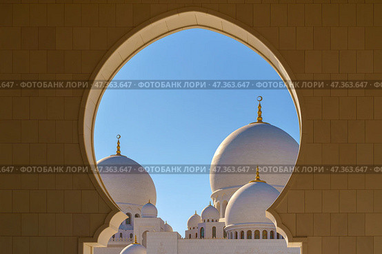 Abu Dhabi, United Arab Emirates - Jan 10 2024, View through the domed arch to the white domes of the Grand Mosque of Sheikh Zayed, at daytime, Abu Dhabi, United Arab Emirates. Редакционное фото, фотограф Сергей Богомяко / Фотобанк Лори
