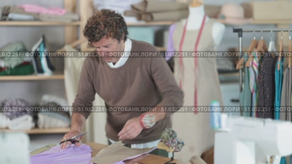 Adult male tailor cutting fabric with scissors in sewing workshop. Стоковое видео, видеограф Яков Филимонов / Фотобанк Лори