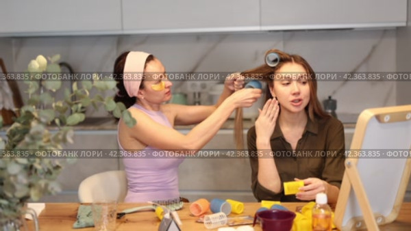 Adult woman curls hair of young woman. Стоковое видео, видеограф Яков Филимонов / Фотобанк Лори