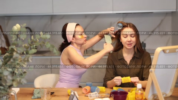 Adult woman curls hair of young woman. Стоковое видео, видеограф Яков Филимонов / Фотобанк Лори