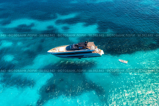 Aerial view of beautiful luxury yacht in blue sea in summer. Sardinia, Italy. Top drone view of boat, sea bay, transparent turquoise water. Travel and vacation. Tropical colorful landscape. Yachting. Стоковое фото, агентство Ingram Publishing / Фотобанк Лори