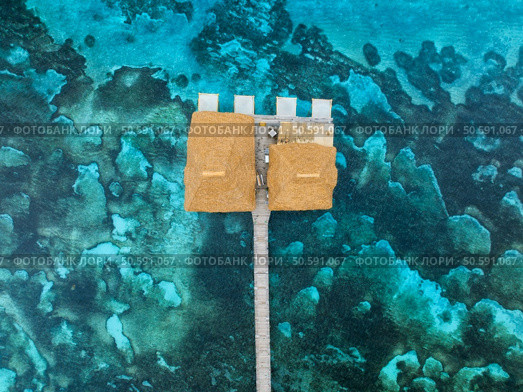 Aerial view of bungalow, jetty, white sandy beach, blue sea on summer sunny day. Restaurant on the ocean. Top view of wooden hotel, turquoise water, green palms. Luxury resort in Zanzibar. Tropical. Стоковое фото, агентство Ingram Publishing / Фотобанк Лори