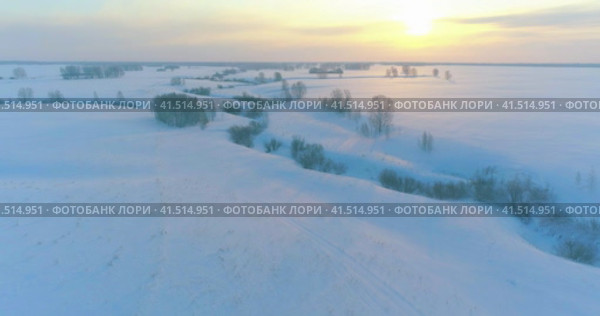 Aerial view of cold arctic field landscape, trees with frost snow, ice river and sun rays over horizon. Extreme low temperature weather. Стоковое видео, видеограф Александр Маркин / Фотобанк Лори