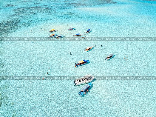 Aerial view of colorful boats, sea bay with azure water on summer day. Mnemba island, Zanzibar. Top drone view of sandbank in low tide, blue sea, sand, yachts. Ocean. Crystal-clear lagoon. Tropical. Стоковое фото, агентство Ingram Publishing / Фотобанк Лори