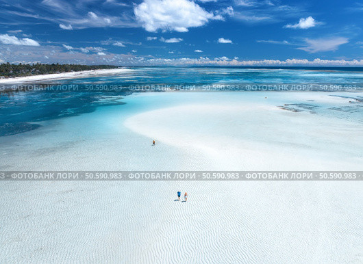 Aerial view of island during low tide, sandbank in ocean, white sandy beach, people, blue sea on sunny summer day in Zanzibar. Top view of sand spit, clear water, sky with clouds. Tropical background. Стоковое фото, агентство Ingram Publishing / Фотобанк Лори