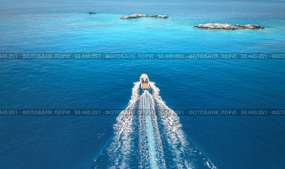 Aerial view of speed boat on blue sea at sunset in summer. Motorboat on sea bay, rocks in clear turquoise water. Tropical landscape with yacht, stones. Top view from drone. Travel in Oludeniz, Turkey. Стоковое фото, агентство Ingram Publishing / Фотобанк Лори