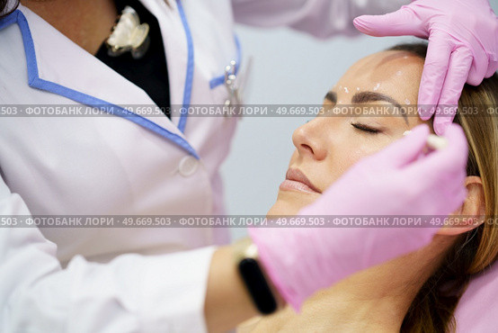 Aesthetic doctor painting on the face of his middle-aged patient the areas to be treated with botulinum toxin.. Aesthetic doctor painting on the face of his patient the areas to be treated with botulinum toxin. Стоковое фото, агентство Ingram Publishing / Фотобанк Лори