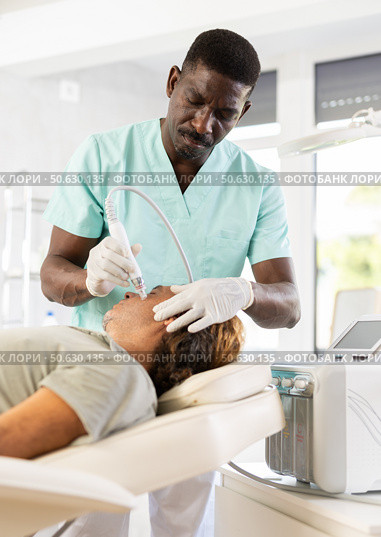 African male cosmetologist performs skin cleansing procedure for man client with beauty machine. Стоковое фото, фотограф Яков Филимонов / Фотобанк Лори