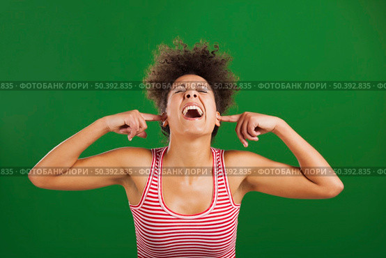 African woman covering ears with her hands, over a green background. Стоковое фото, агентство Ingram Publishing / Фотобанк Лори