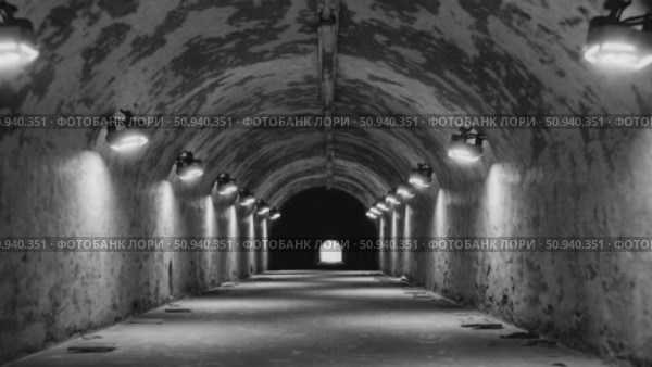 Aged tunnel with textured walls glowing under rows of lights, revealing mysterious passage leading toward luminous distant opening. Стоковое AI-видео, аниматор Данил Руденко / Фотобанк Лори