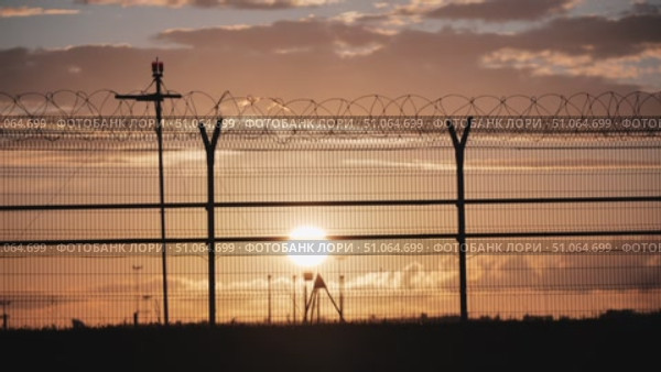 Airport service truck passing behind barbed wire fence at sunset. Стоковое видео, видеограф Mikhail Davidovich / Фотобанк Лори