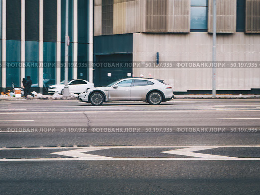 All-electric car Porsche Taycan in motion. Speeding in city road concept. Редакционное фото, фотограф Константин Григорьев / Фотобанк Лори