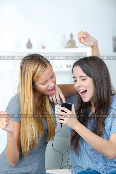 amazed roommates watching offers on line with a smart phone. Стоковое фото, агентство Ingram Publishing / Фотобанк Лори