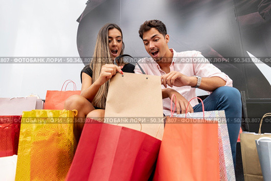 amazed young couple looking inside shopping bags. Стоковое фото, агентство Ingram Publishing / Фотобанк Лори