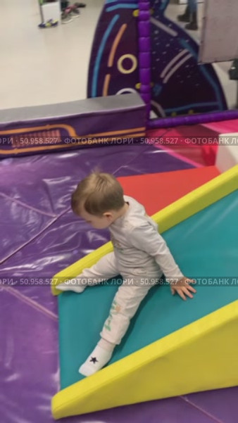 An adorable video of a toddler giggling with delight while sliding down a playground slide, ending with a heart-melting smile. This joyful childhood moment captures pure happiness, perfect for parenting content, children's product promotions, or lifestyle projects. Стоковое видео, видеограф Виктор Ветошкин / Фотобанк Лори