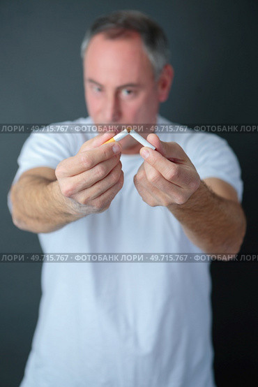 an adult man breaking cigarette. Стоковое фото, агентство Ingram Publishing / Фотобанк Лори