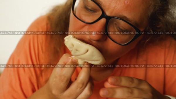 An attractive woman in glasses eats khinkali in a cafe. Georgian cuisine. Close-up. The camera moves following the hands of a woman who takes khinkali from the plate. Стоковое видео, видеограф Воловодов Владимир / Фотобанк Лори