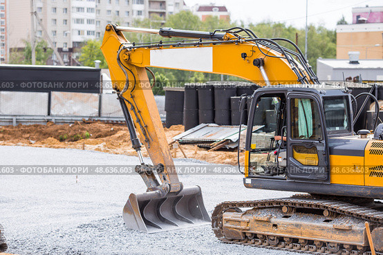 An excavator on a construction site in close-up. The excavator rams the crushed stone with a bucket for construction. Heavy machinery for construction and landscaping. Стоковое фото, фотограф Photojuli / Фотобанк Лори