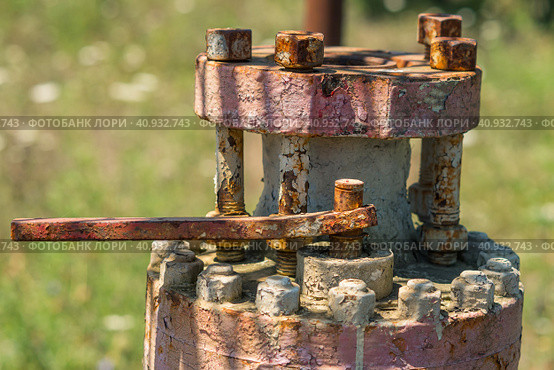 An old flange with rusty bolts and peeling paint abandoned in the field after the end of oil production. Pollution of the environment. Стоковое фото, фотограф Воловодов Владимир / Фотобанк Лори