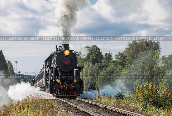 An old Soviet steam locomotive of the L series. The Ruskeala Express retro train is on its way to the mountain park. Thick smoke is coming from the chimney. Russia, Republic of Karelia, Sortavala, August 10, 2025. Редакционное фото, фотограф Photojuli / Фотобанк Лори