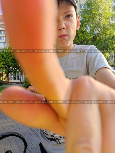 An original, funny shot where the junior boy almost covers the lens with his finger. The kid of about nine makes an angry face and feigns resistance. Children's behavior: mischief and disobedience. Стоковое фото, фотограф Анатолий Власов / Фотобанк Лори