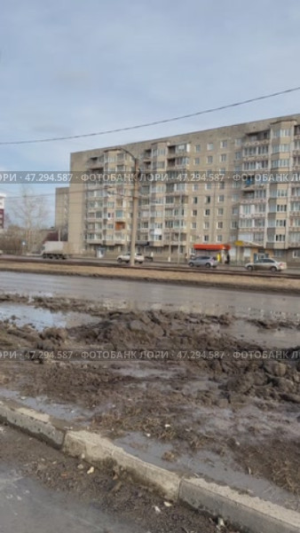 ANGARSK, IRKUTSK REGION, RUSSIA - March 20, 2025: Vertical video of spring cleaning of city roads. An excavator uses a bucket to clear the roadside of winter ice and mud. Редакционное видео, видеограф Виктория Катьянова / Фотобанк Лори