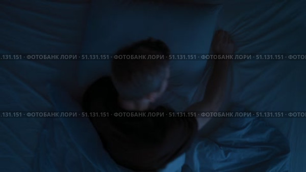 Anxious young man suffers from insomnia, turning in bed, trying to fall asleep. Стоковое видео, видеограф Arsenii Palivoda / Фотобанк Лори