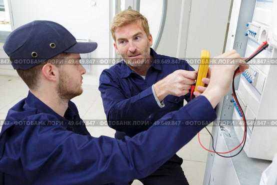apprentice electrician using a multimeter on a fusebox. Стоковое фото, агентство Ingram Publishing / Фотобанк Лори