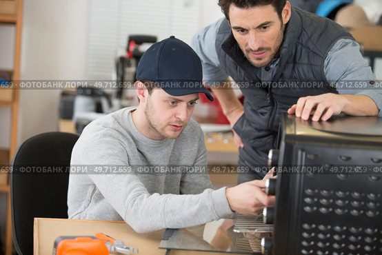 apprentice electrician working on appliance under supervision. Стоковое фото, агентство Ingram Publishing / Фотобанк Лори