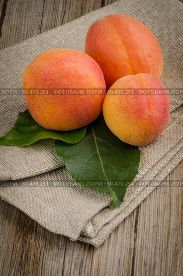 Apricots with leaves on the wooden table. Стоковое фото, агентство Ingram Publishing / Фотобанк Лори