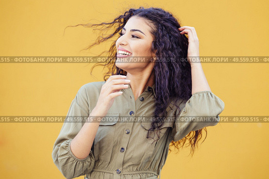 Arab woman with curly hair moved by the wind in urban background. Arab woman with curly hair moved by the wind. Стоковое фото, агентство Ingram Publishing / Фотобанк Лори
