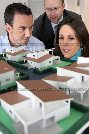Architect showing scale model of house to buyers. Стоковое фото, агентство Ingram Publishing / Фотобанк Лори