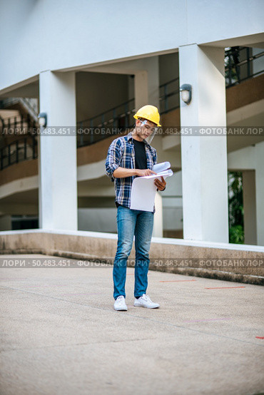 Architects hold the building plan and check the work. Стоковое фото, агентство Ingram Publishing / Фотобанк Лори