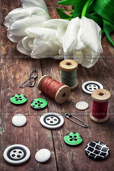 armful white tulip and buttons for clothing on deprecated wooden background.the image is tinted in vintage style. thread and buttons. Стоковое фото, агентство Ingram Publishing / Фотобанк Лори