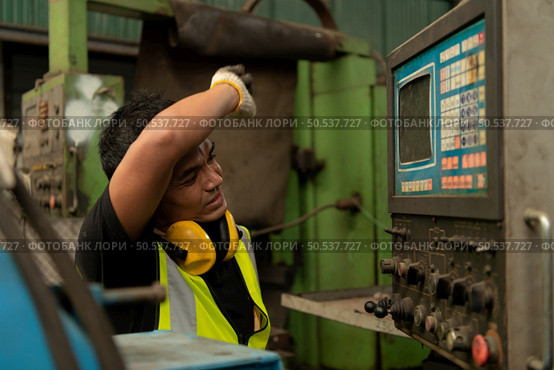 Asian mechanic working in a mechanical factory Repairing old machines to bring them back to normal operation. Стоковое фото, агентство Ingram Publishing / Фотобанк Лори