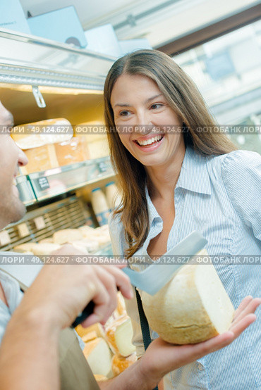 Assistant cutting chunk of cheese for female customer. Стоковое фото, агентство Ingram Publishing / Фотобанк Лори