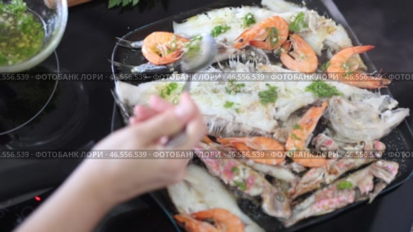 Assortment of fried shrimp, red mullet, sardines and megrim fillet seasoned with aromatic green herb oil sizzling in hot skillet on stove, creating hearty seafood dish. Стоковое видео, видеограф Яков Филимонов / Фотобанк Лори