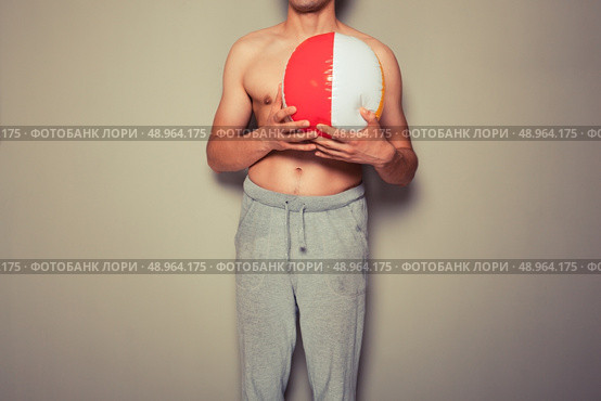 Athletic young man is holding a beach ball. Стоковое фото, агентство Ingram Publishing / Фотобанк Лори