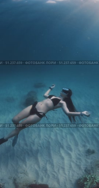 Attractive woman meditate underwater in blue ocean with undersea sunshine. Стоковое видео, видеограф Wonderful nature / Фотобанк Лори