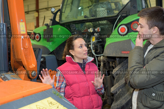 attractive woman selling brand new tractor to beginner farmer. Стоковое фото, агентство Ingram Publishing / Фотобанк Лори